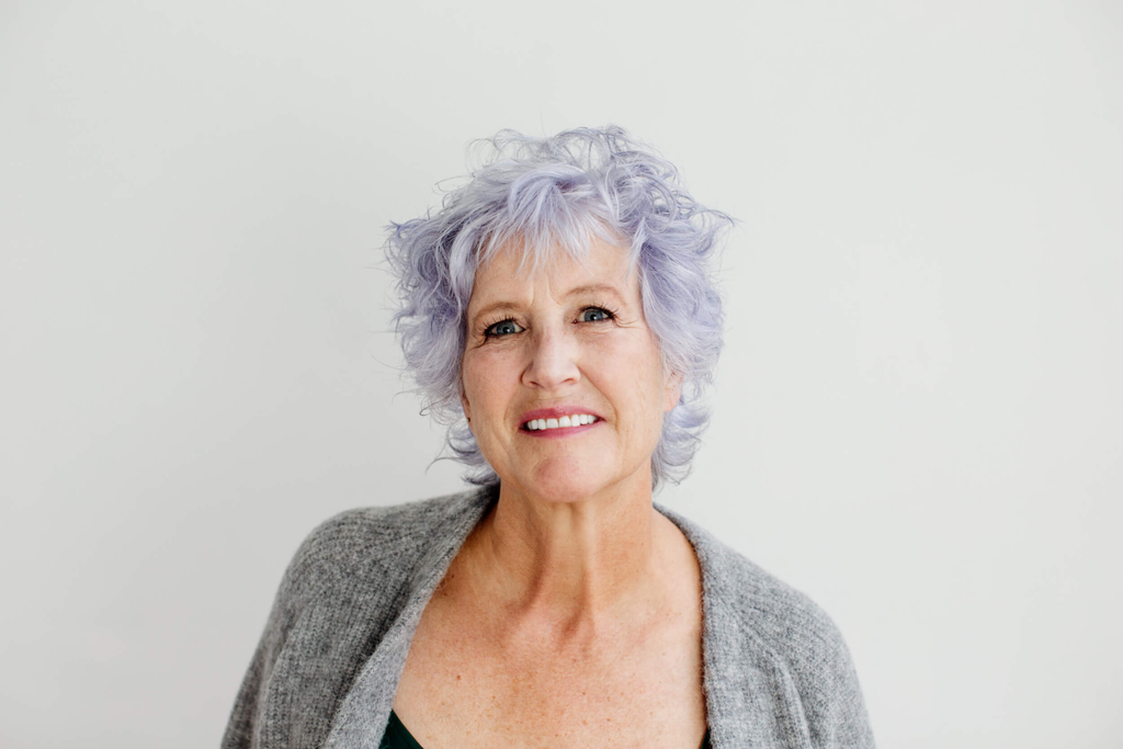 Older woman with short lavender hair. 