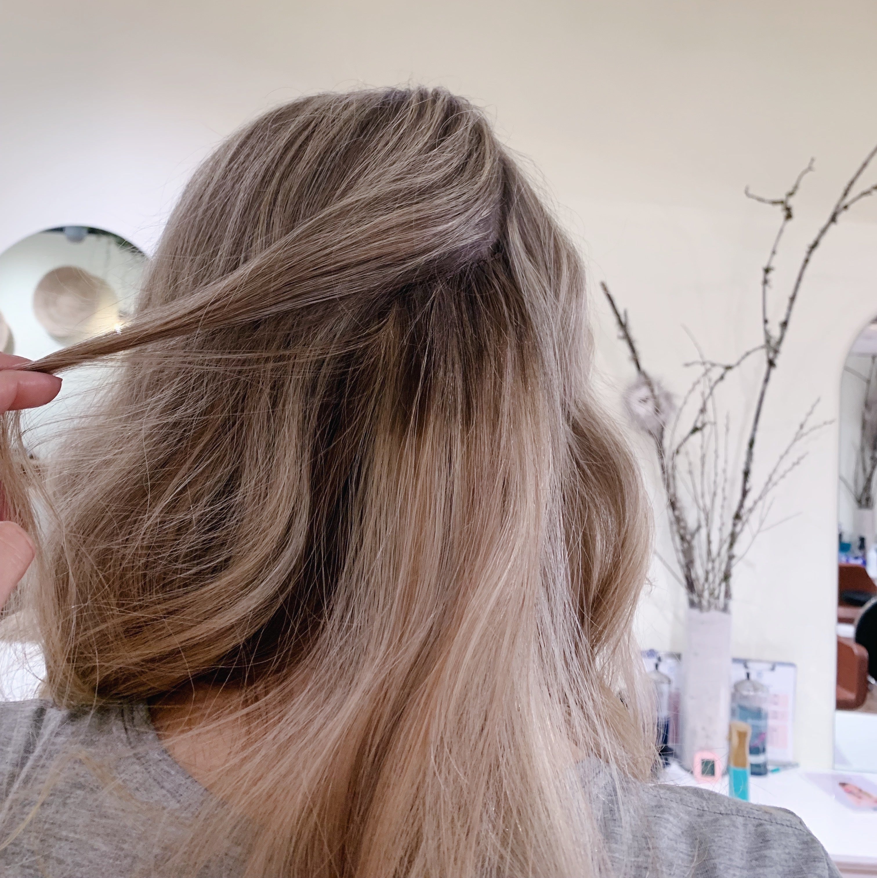 Woman showing her hair extensions, holding up a strand of hair and showing the hairline