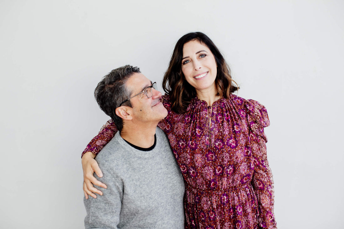 Picture of a man and woman, the woman is wearing an Ulla Johnson dress and the man is wearing a CP and co sweater in grey. The man and woman are owners of a hairsalon.