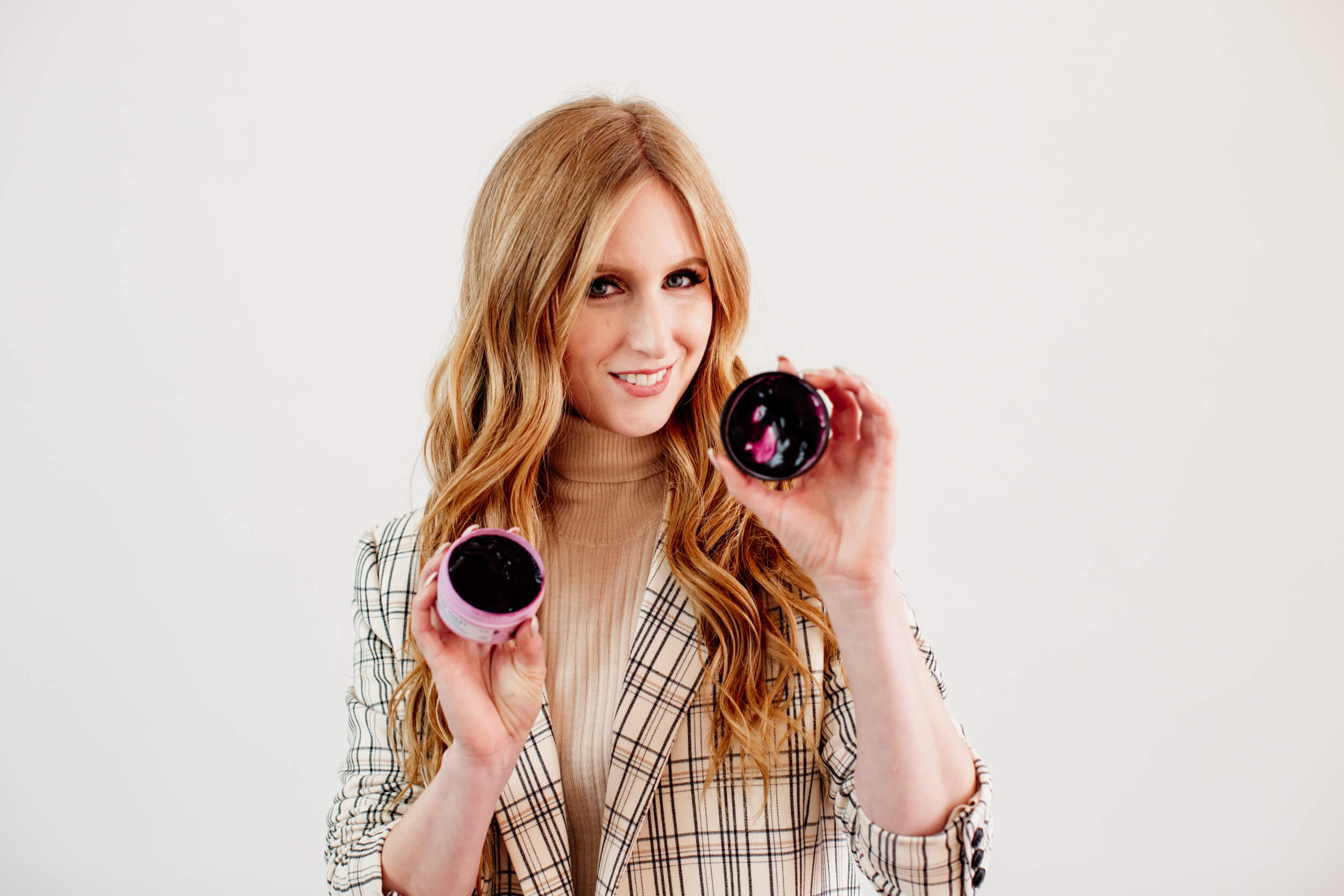 Woman with red long hair is holding a Maria Nila hair colour refresh product in her hands