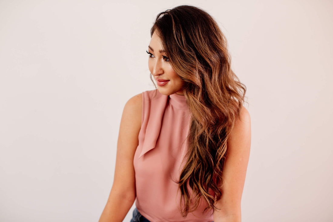 Woman is long hair extensions and is wearing a pink blouse. 