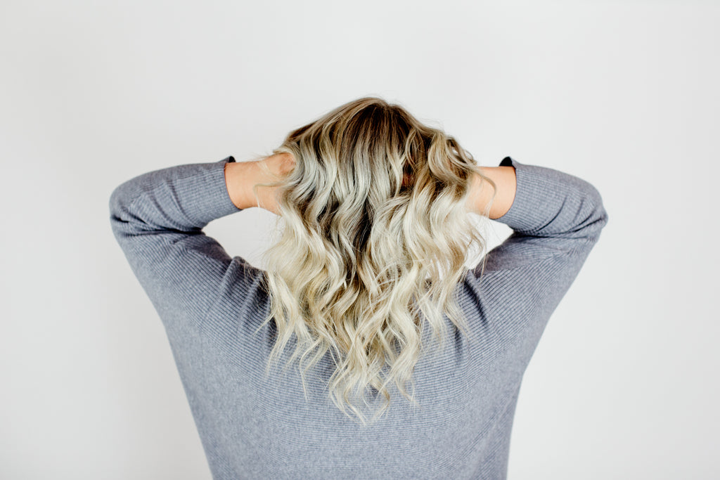 Woman with blonde hair showing the back of her newly styled hair. 