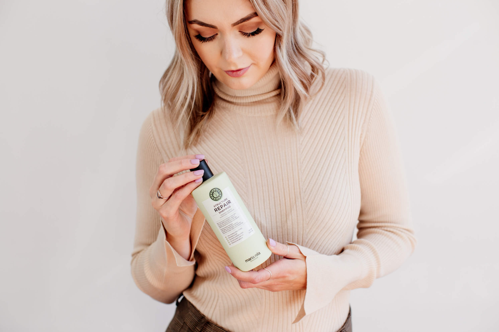 Woman with short blonde hair holding Maria Nila hair conditioner. 