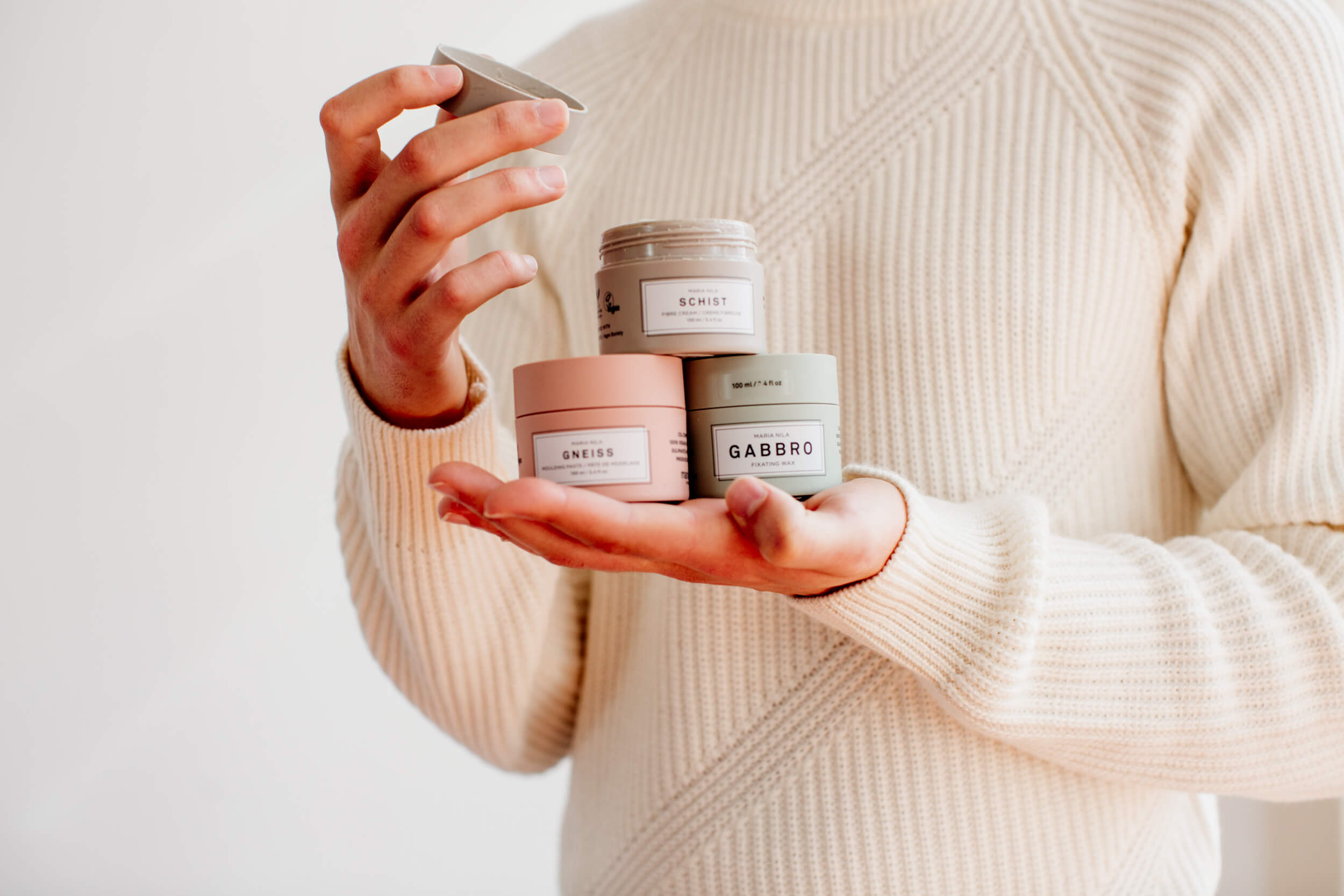 Man holding styling products for men. He is holding Maria Nila hair wax.