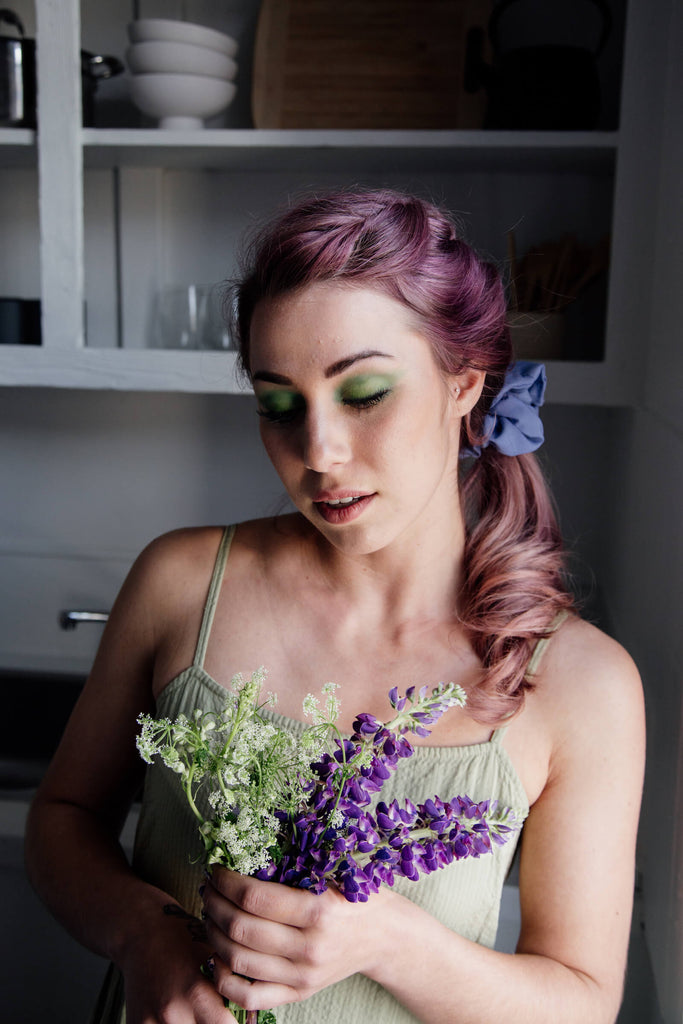 A woman with braided hair holds some lilacs.