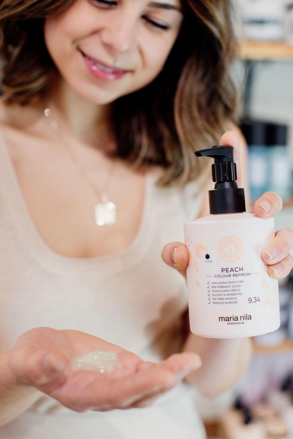 woman is holding a bottle of the colour refresh in peach